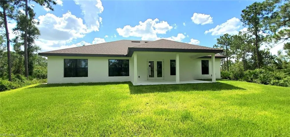 Rear view of house with a patio and a lawn