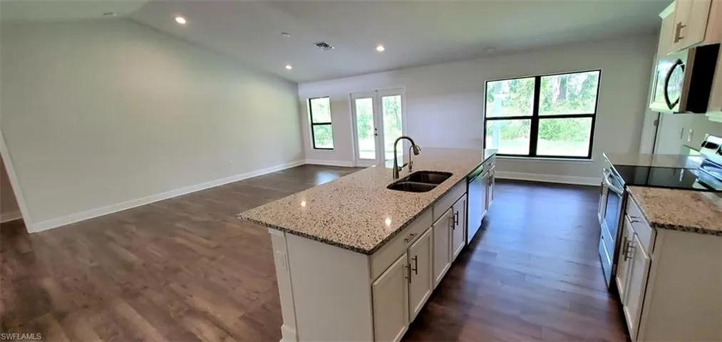 Kitchen featuring appliances with stainless steel finishes, white cabinets, sink, a kitchen island with sink, and dark hardwood / wood-style flooring