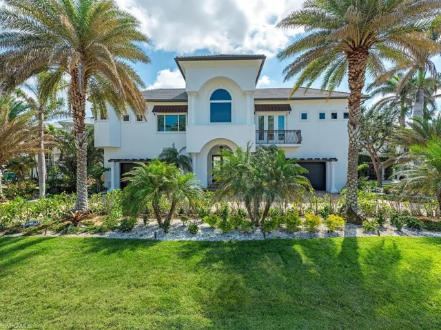 Mediterranean / spanish-style home with a garage, a front yard, a balcony, and stucco siding