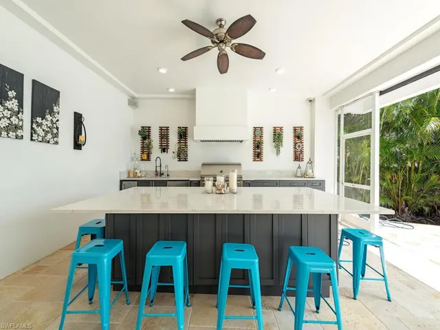 Kitchen with a large island, recessed lighting, stone tile flooring, a sink, and premium range hood