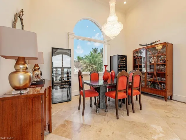 Dining area with crown molding, a notable chandelier, a towering ceiling, and baseboards