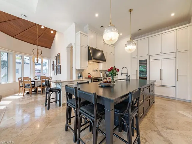 Kitchen with paneled fridge, under cabinet range hood, a sink, wood ceiling, and decorative backsplash