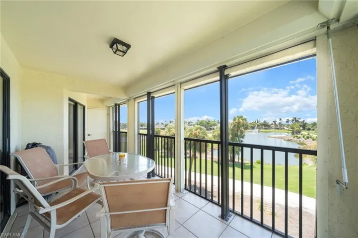 Sunroom with a textured wall, tile patterned floors, a balcony, and a water view