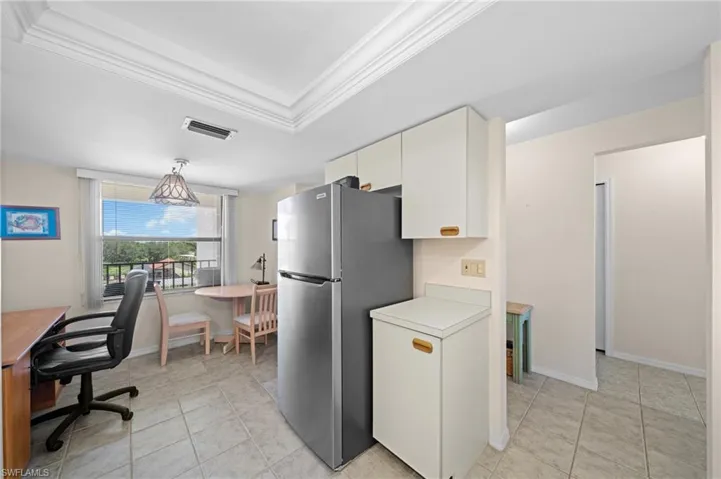 Kitchen featuring light countertops, ornamental molding, light tile patterned floors, freestanding refrigerator, and a tray ceiling