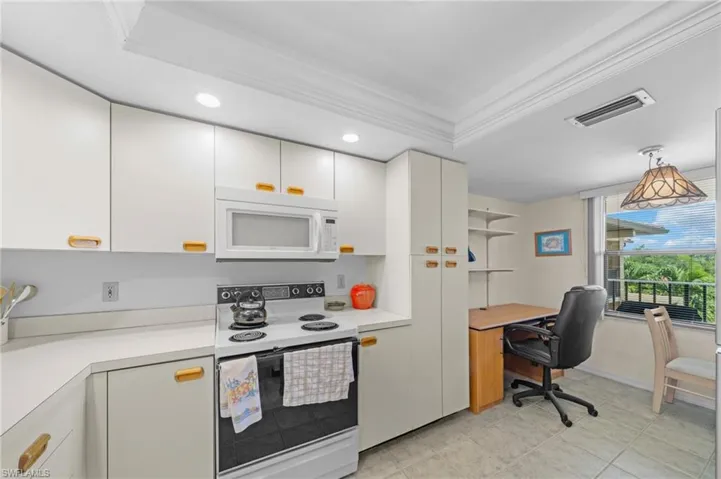 Kitchen with white appliances, light countertops, white cabinets, open shelves, and crown molding