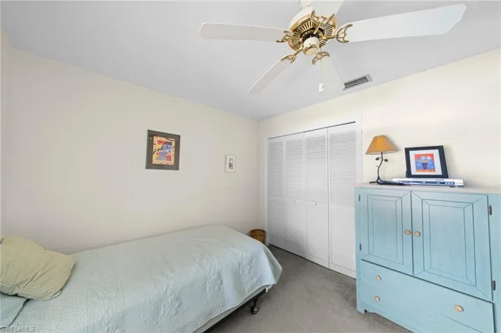 Bedroom featuring light carpet, ceiling fan, and a closet