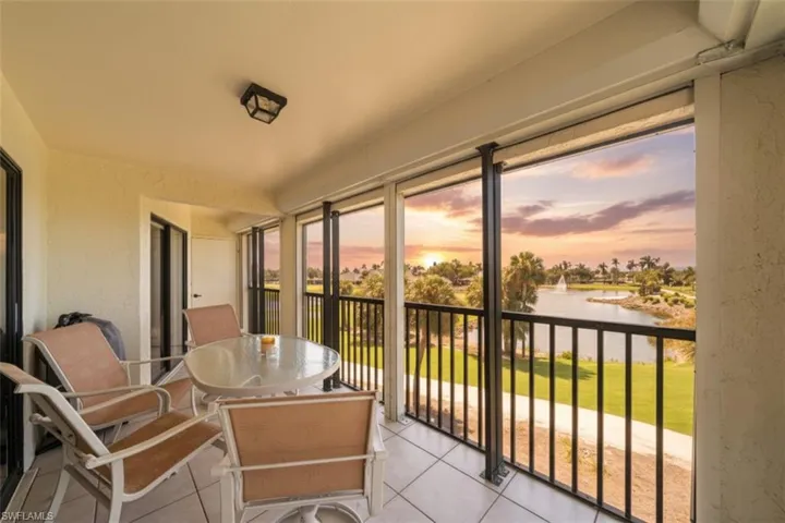 Sunroom / solarium with a water view, a balcony, tile patterned flooring, a textured wall, and outdoor dining area