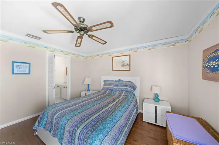 Bedroom featuring wood finished floors, a ceiling fan, and connected bathroom