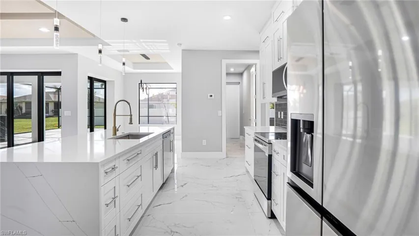 Kitchen featuring white cabinets, a kitchen island with sink, pendant lighting, and stainless steel appliances