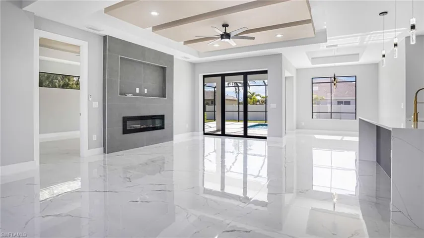 Unfurnished living room with a fireplace, ceiling fan, and a raised ceiling