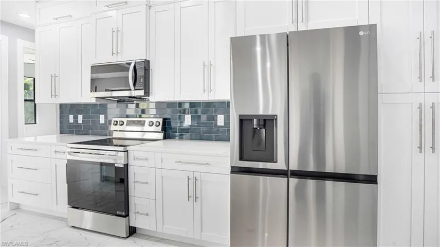 Kitchen featuring white cabinets, stainless steel appliances, and backsplash