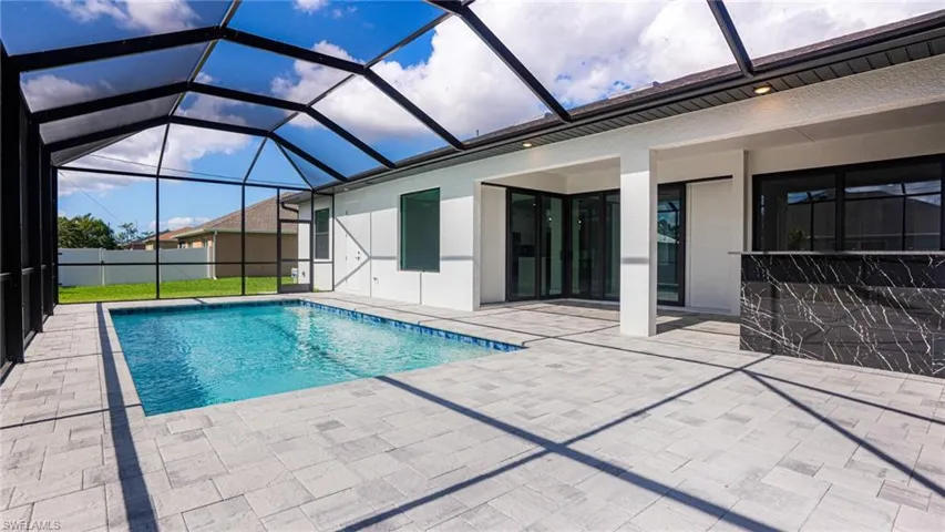 View of swimming pool featuring glass enclosure and a patio area