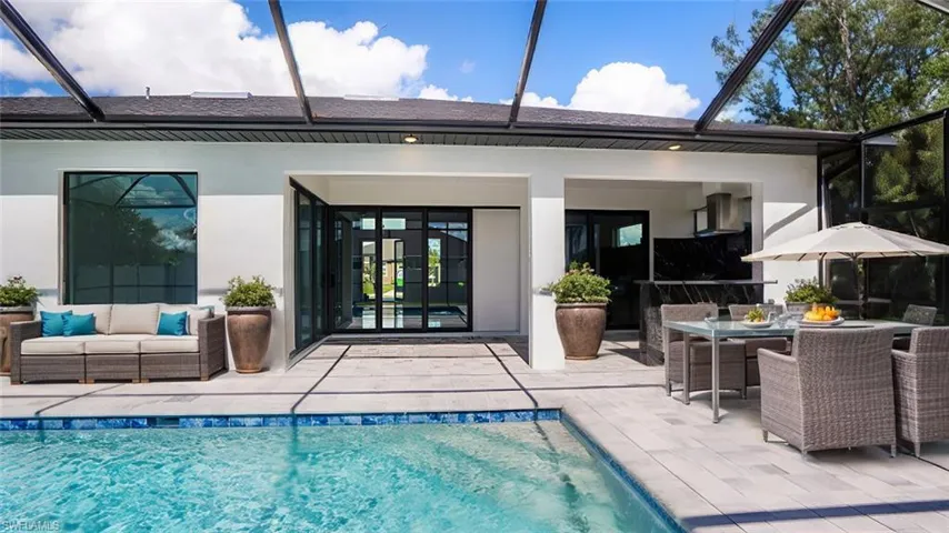 Rear view of house featuring glass enclosure, a patio area, and an outdoor hangout area
