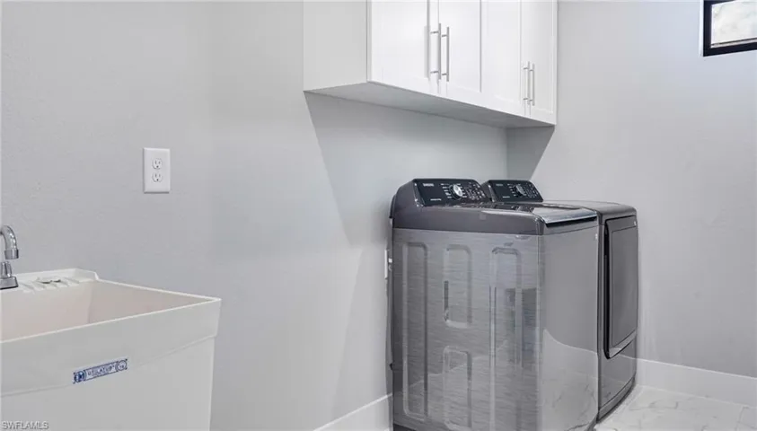 Washroom with cabinets, sink, and washer and dryer
