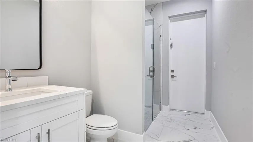 Bathroom featuring a shower with door, vanity, and toilet