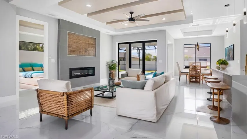 Living room featuring ceiling fan, a tile fireplace, and a tray ceiling