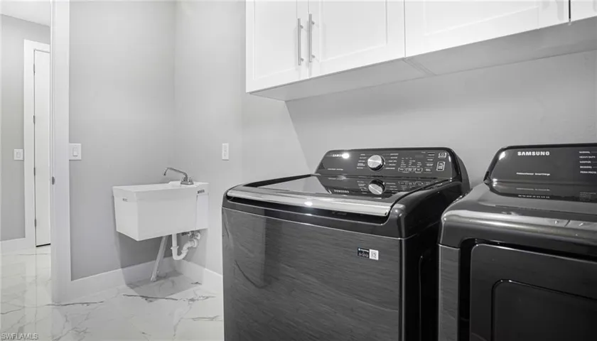 Laundry room with cabinets, washer and dryer, and sink