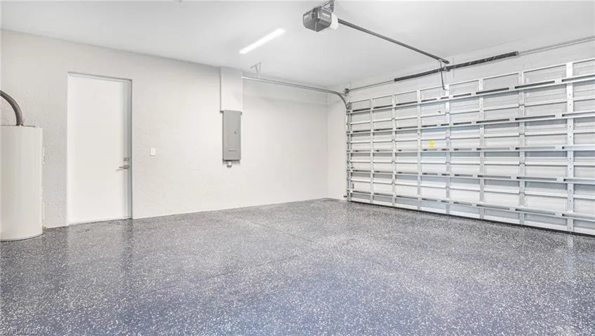 Garage featuring electric panel, a garage door opener, and water heater