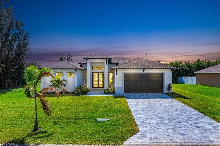 View of front facade featuring a garage and a yard