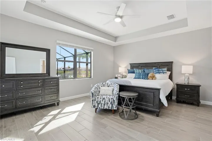 Bedroom featuring a raised ceiling, wood tiled floors, and ceiling fan