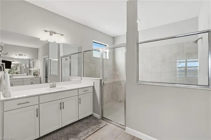 Bathroom featuring vanity, a stall shower, and light wood-style floors