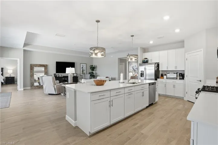 Kitchen featuring pendant lighting, white cabinetry, light wood-type flooring, appliances with stainless steel finishes, and open floor plan