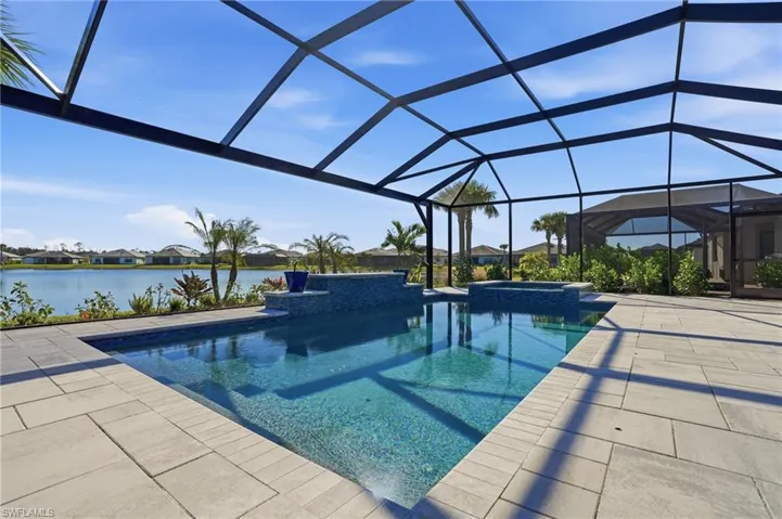 View of pool featuring a lanai, a sunroom, a residential view, a pool with connected hot tub, and a water view