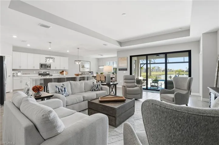 Living area featuring light wood-style floors, a raised ceiling, and recessed lighting
