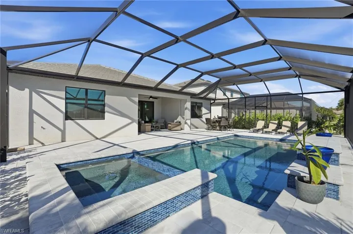 View of swimming pool featuring a sunroom, a pool with connected hot tub, glass enclosure, ceiling fan, and a patio