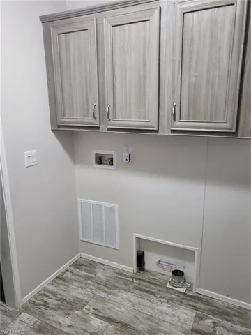 Laundry room featuring washer hookup, cabinet space, and light wood-style floors