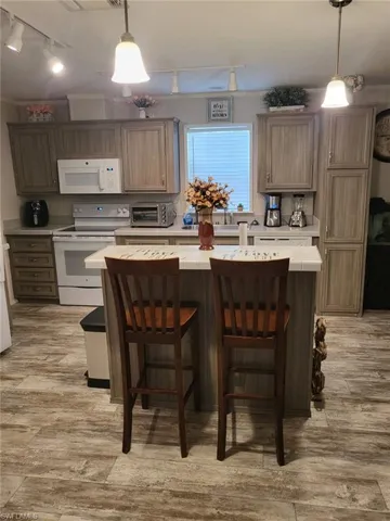 Kitchen featuring track lighting, tile counters, a center island, and white appliances