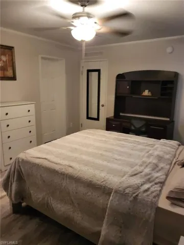Bedroom featuring ceiling fan, dark wood-style flooring, and crown molding