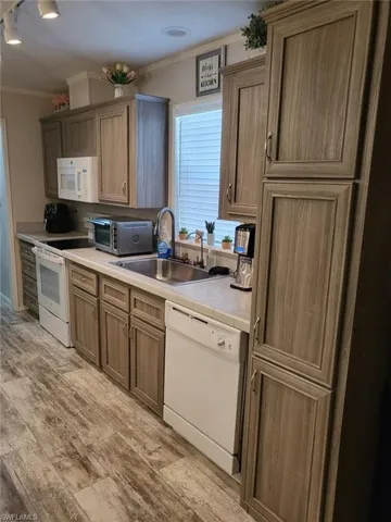 Kitchen featuring tile countertops, crown molding, white appliances, track lighting, and light wood-style flooring