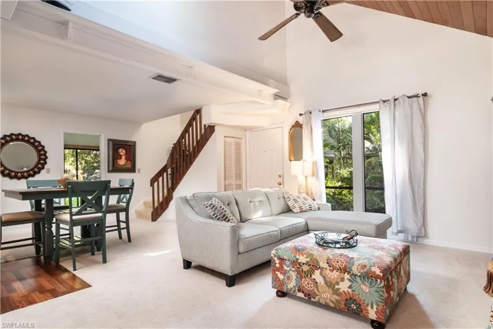 Living area with carpet, healthy amount of natural light, a ceiling fan, and high vaulted ceiling