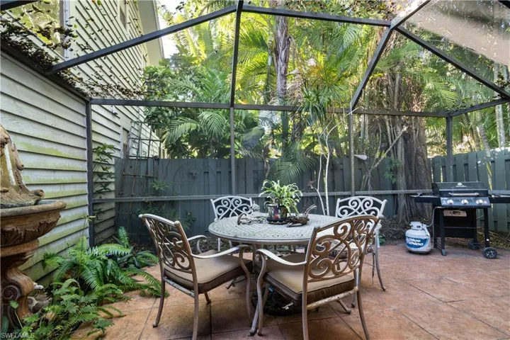 View of patio featuring glass enclosure, grilling area, and outdoor dining space