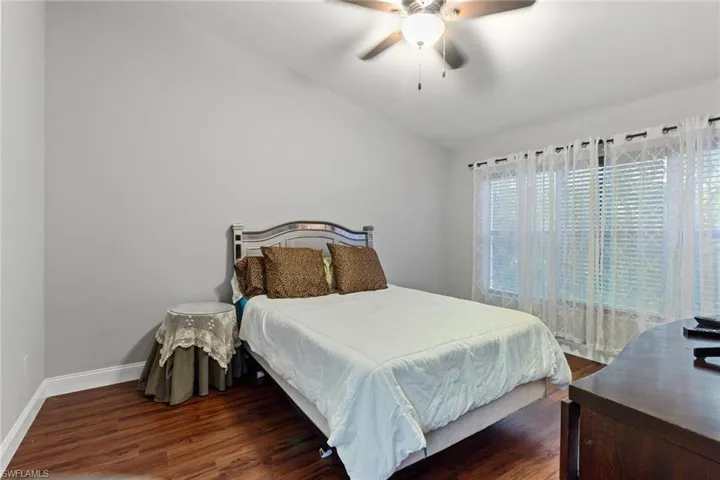 Bedroom featuring dark wood-type flooring, ceiling fan, and vaulted ceiling