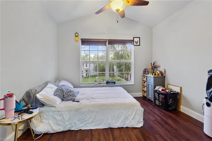 Bedroom featuring dark wood-type flooring, vaulted ceiling, and ceiling fan