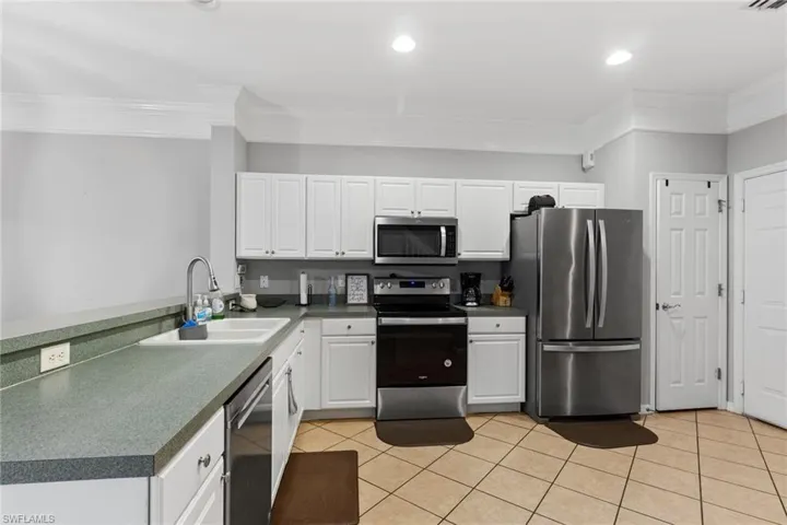 Kitchen with crown molding, sink, white cabinets, and stainless steel appliances