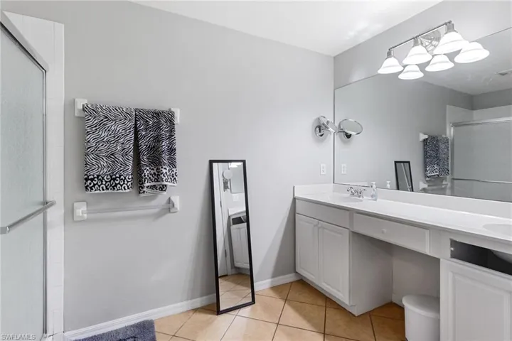Bathroom with vanity, tile patterned floors, and a shower with shower door