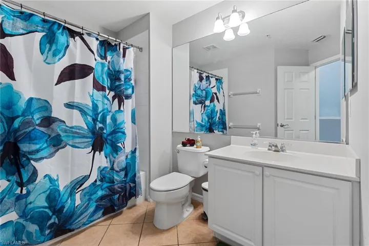 Full bathroom with toilet, vanity, shower / bath combination with curtain, and tile patterned floors
