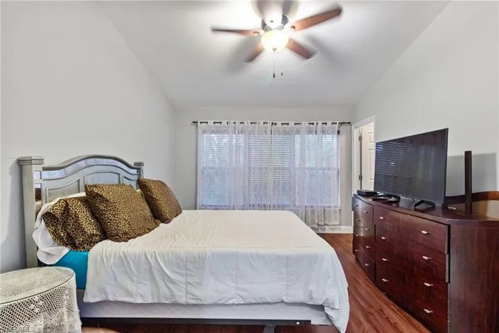 Bedroom with vaulted ceiling, ceiling fan, and dark hardwood / wood-style flooring