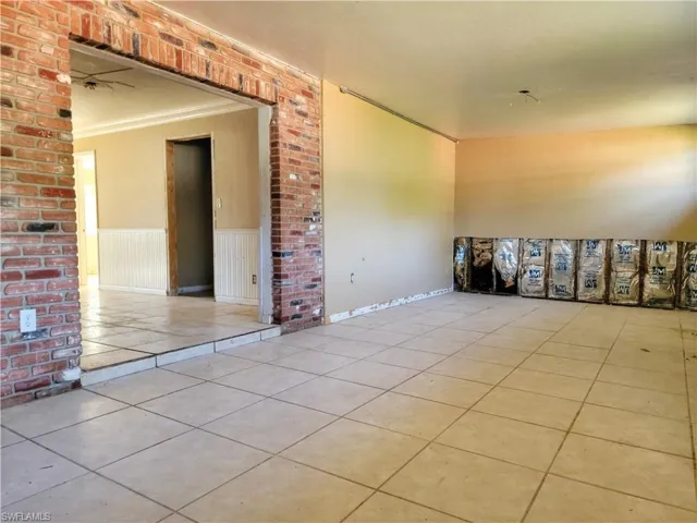Tiled spare room featuring ornamental molding and wainscoting