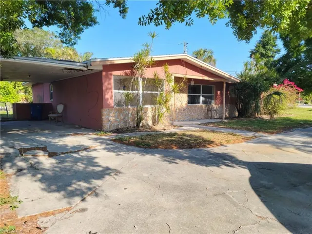 View of front facade featuring a carport, concrete driveway, and stone siding