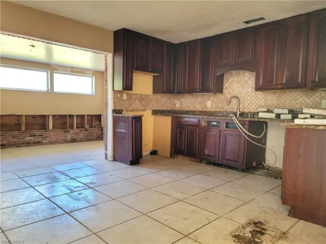 Kitchen featuring tasteful backsplash, stone counters, a sink, and visible vents