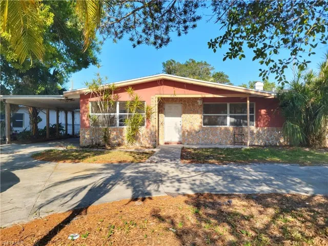 View of front of house featuring concrete driveway, an attached carport, and stone siding