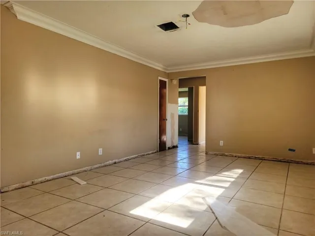 Spare room with ornamental molding, light tile patterned flooring, and baseboards