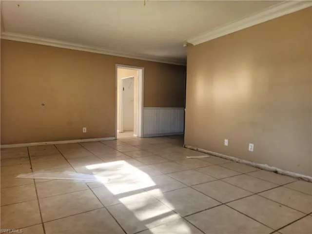 Spare room with tile patterned flooring, baseboards, and crown molding