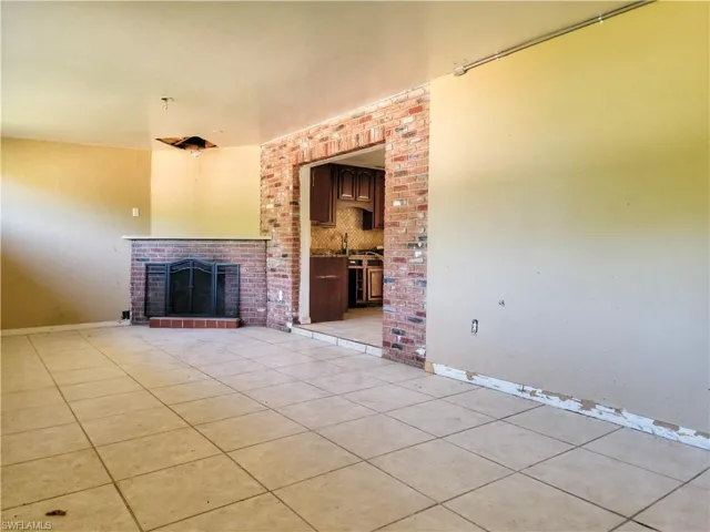 Unfurnished living room featuring light tile patterned floors, a fireplace, and baseboards