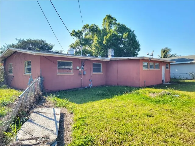 Rear view of house with a yard, fence, and stucco siding