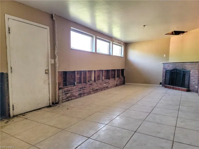 Unfurnished living room featuring brick wall, a fireplace, and tile patterned floors